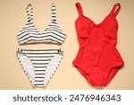 Two beautiful swimsuits on beige background, flat lay