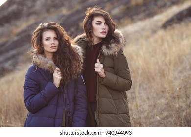 Two Beautiful Woman In Fashion Winter Clothes Outside. Trendy Autumn And Winter Clothes. Down Jacket.