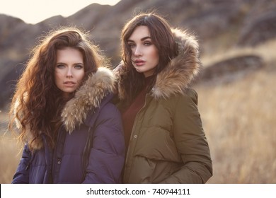 Two Beautiful Woman In Fashion Winter Clothes Outside. Trendy Autumn And Winter Clothes. Down Jacket.