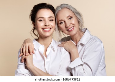 Dos bellas mujeres en pantalones blanco abrazan el retrato hacia adelante. Captura de pantalla de estudio de la abuela y nieta toothy sonriente, madre e hija mayores, ancianos y hermanas jóvenes. Familia feliz Foto de stock