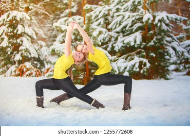 Two Beautiful Women Doing Yoga Outdoors In The Snow