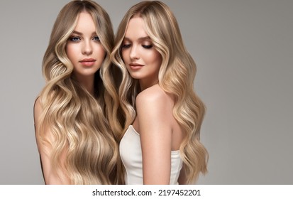 Two beautiful women    with hair coloring in ultra blond. Stylish hairstyle curls done in a beauty salon. Fashion girls , cosmetics and makeup. - Shutterstock ID 2197452201