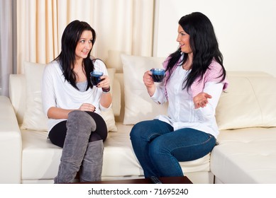 Two Beautiful Women Having Conversation  Drinking Coffee And Sitting On Couch Home