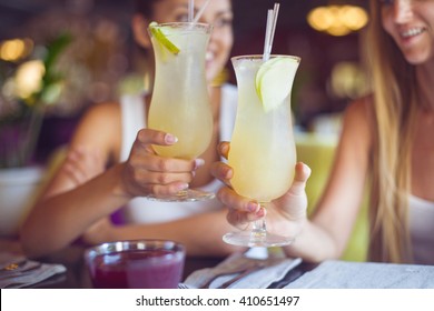 Two beautiful women having fun in a bar drinking cocktails