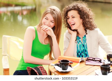 Two Beautiful Women Laughing Over A Coffee At The River Side Terrace - Vibrat Summer Colors