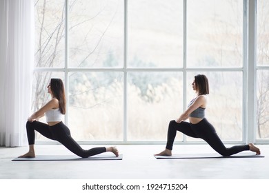 Two beautiful women performing synchronised yoga in a modern studio