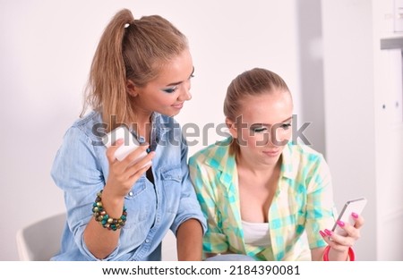 Two beautiful women sending messages with mobile