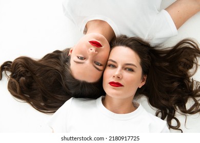 Two beautiful women twin sisters close-up face portrait, laying on floor - Shutterstock ID 2180917725
