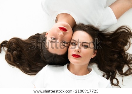 Two beautiful women twin sisters close-up face portrait, laying on floor
