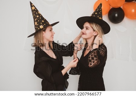 Two beautiful women wearing witch hat, halloween costume on white background