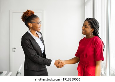 two beautiful young african women in the office shaking hands 