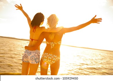 two beautiful young girlfriends opened her hands with delight at the blue sea and sky - Powered by Shutterstock