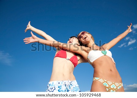 two beautiful young girlfriends opened her hands with delight at the blue  sky
