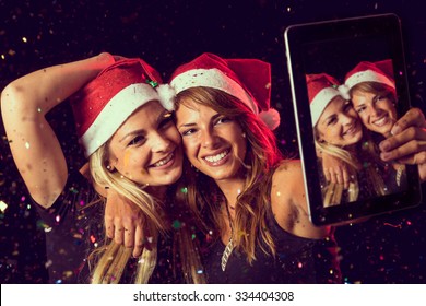 Two beautiful young girls having fun at New Year's Eve party and taking a midnight selfie