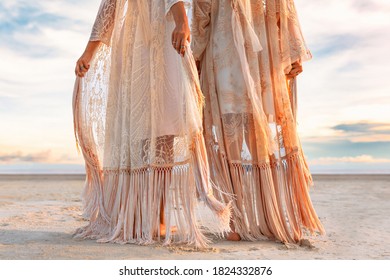 two beautiful young woman in elegant boho dresses oudoors at sunset