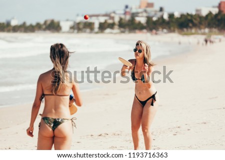 Two beautiful young woman playing with racket at the beach