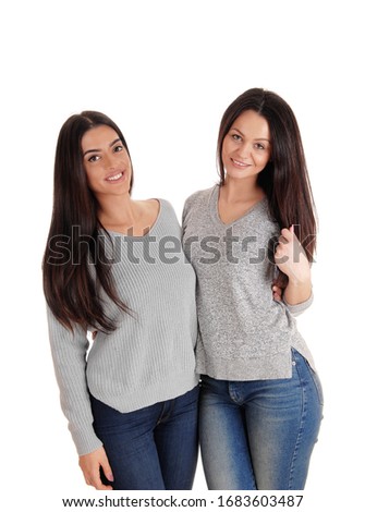 Two beautiful young woman standing site to site in jeans 
looking at the camera, isolated for white background
