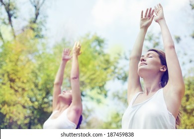 Two Beautiful Young Women Doing Yoga Class In Nature.