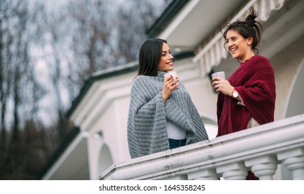 Two beautiful young women enjoying together on terrace at their country house.