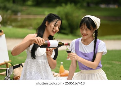 Two beautiful young women enjoying picnic with wine while sitting on a grassy area. - Powered by Shutterstock