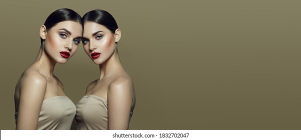 Two beautiful young women with gathered dark hair with perfect skin and bright red lips in beige tops on a beige background in the studio.