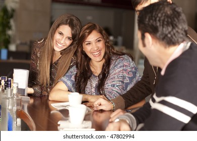 Two beautiful young women with great teeth enjoying their lunch break, sitting at a bar, flirting, drinking coffee, smiling - Powered by Shutterstock