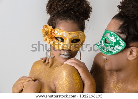 Two beautiful young women with their bodies painted in gold. Young African-American women dressed up as masks and with their bodies painted for the carnival.