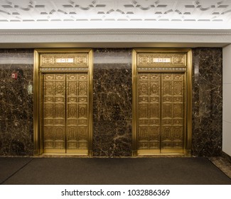 Two beautifully decorated golden elevators in classic office building in an urban environment with no people