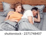 Two in bed, a woman looks with pity at the offended man who turned away. Relationship concept