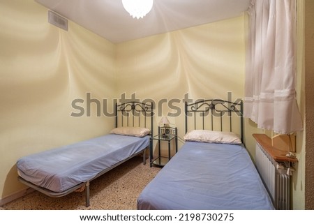 Two beds in a small simple bedroom in a hostel, motel or guest house. Concept of budget accommodation for rent or travel