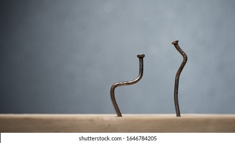 Two bent nails driven into a board. Concept stoop, sciatica and degenerative disc disease - image