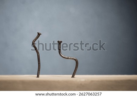 Two bent nails driven into a board. Concept stoop, sciatica and degenerative disc disease - image