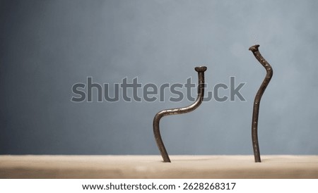 Two bent nails driven into a board. Concept stoop, sciatica and degenerative disc disease - image