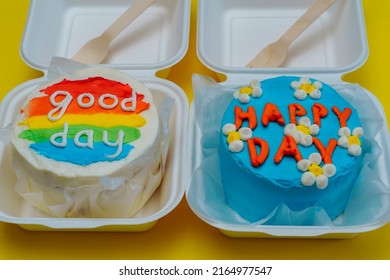 Two bento cake box blue cake with daisies, happy day inscription. and with rainbow lettering good day Delicious beautiful dessert. Small gift holiday. Korean style cakes box fork one person.