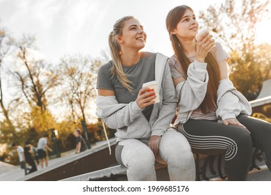 Two Best Female Friends Sitting At The Skate Park And Joying In Coffee To Go.