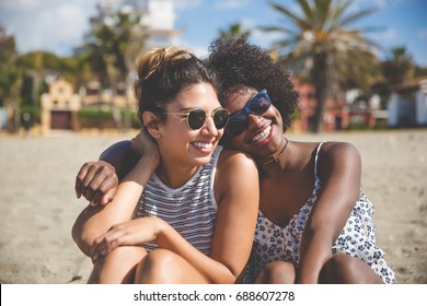 Two best female friends sitting together on beach smiling - Powered by Shutterstock