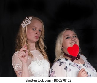 Two Best Friends In A Photobooth With Props On A Black Background Having Fun