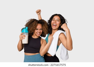 Two best friends are ready to go to the gym, one of them holds a protein shake, raising fist after a victory, winner concept. - Powered by Shutterstock