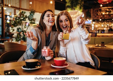 Two best friends sitting in coffee bar or restaurant after shopping and happily talking together.  - Powered by Shutterstock