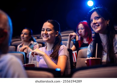 Two best friends are watching a movie in cinema and they are eating popcorn. - Powered by Shutterstock