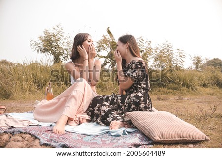 Two bestfriends share lighthearted stories while having a picnic in a meadow. Boho inspired outfits and setting.