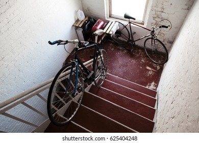 Two Bicycles In A Stairway Of A Residential Building.