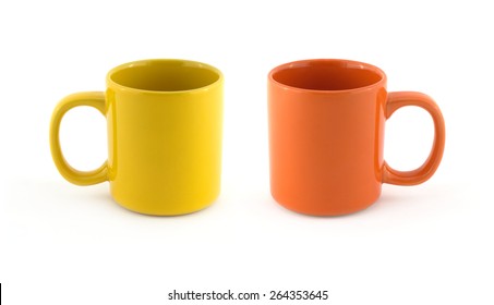 Two big empty yellow and orange tea or coffee cups isolated on white close up. Dishes studio shot