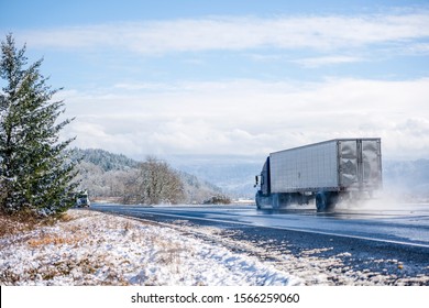 Two Big Rigs Semi Trucks With Different Semi Trailers Go Towards Each Other Following Each His Own Route On The Winter Dangerous Wet Road Raising Clouds Of Water Dust From Melting Snow