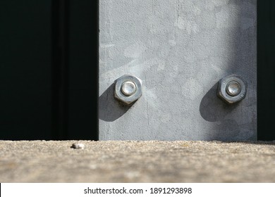 Two Big Screws In A Steel Plank Behind A Stone Wall