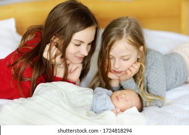 Two Big Sisters Admiring Their Sleeping Newborn Brother. Two Young Girls Holding Their New Baby Boy. Kids With Large Age Gap. Big Age Difference Between Siblings. Big Family.