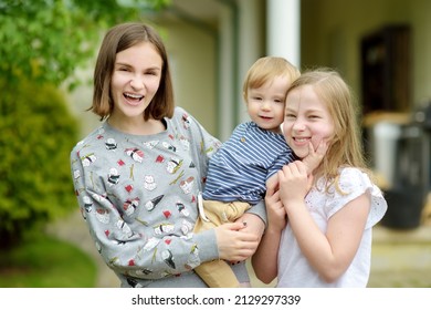 Two Big Sisters And Their Toddler Brother Having Fun Outdoors. Two Young Girls Holding Baby Boy On Summer Day. Children With Large Age Gap. Big Age Difference Between Siblings. Big Family.