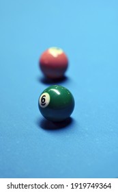 Two billiard balls are displayed. Green in the foreground, brown in the background. Image with selective focus.