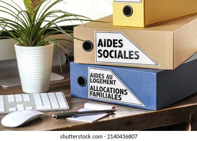 two binders with the french words that means social assistance, family allowances and housing assistance on an office - Shutterstock ID 2140436807