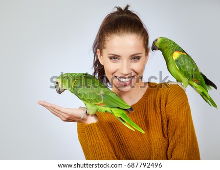 Two bird, cute parrots, sit on woman. Studio shoot